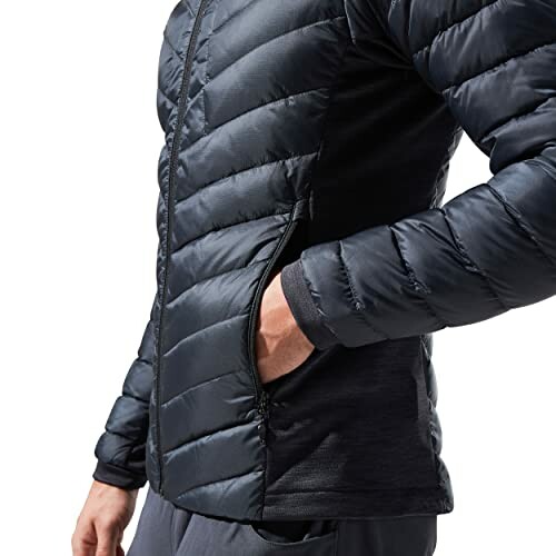 Person wearing a black puffer jacket with hand in pocket.