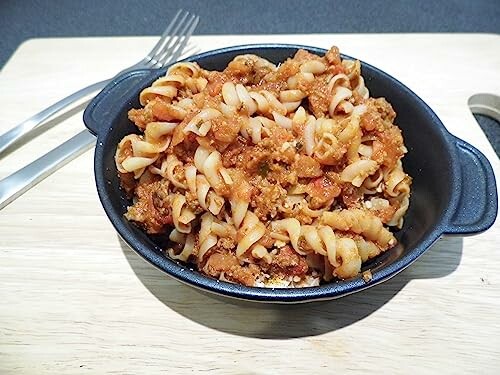 Fusilli pasta with tomato meat sauce in a black bowl.