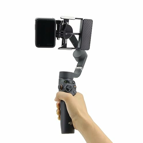 Hand holding a camera gimbal with a smartphone.