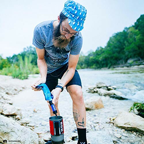 Man using water filter by a stream