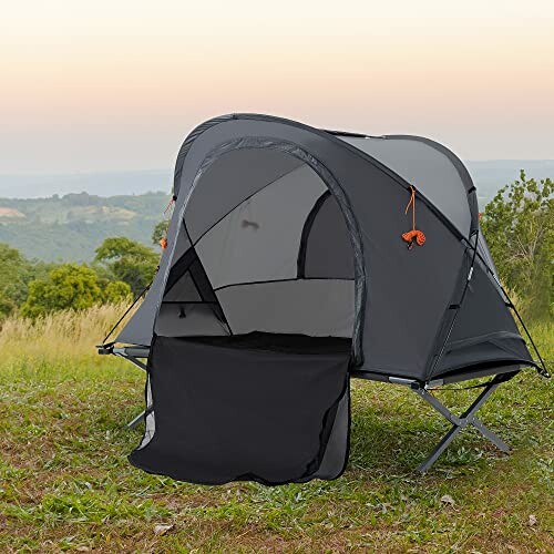 Portable camping tent on a grassy hill with scenic background.