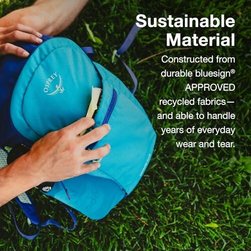 Person holding a blue backpack with text about sustainable material.