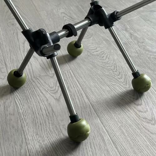 Close-up of a wheelchair frame with green wheels on a wooden floor.